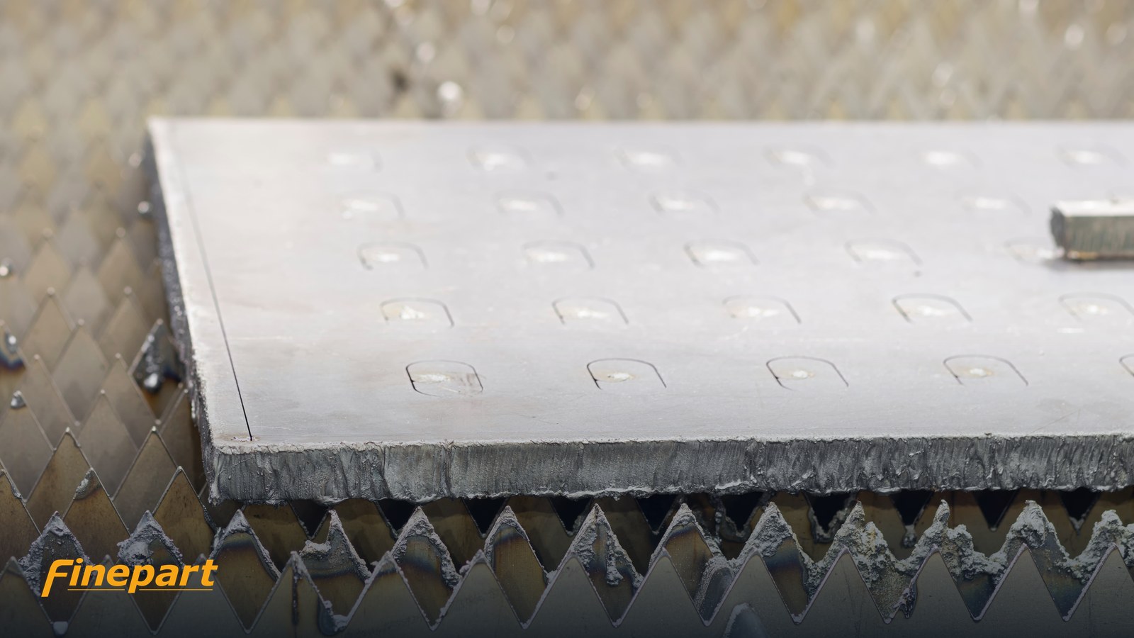 Laser-cut metal edge showing dross and heat discolouration compared with a clean waterjet edge